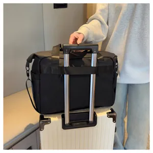 Vue détaillée du grand sac de voyage sportif noir avec sangle pour fixation sur valise.