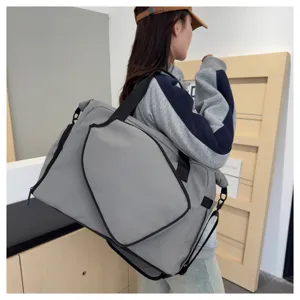 Vue détaillée d'un grand sac de sport gris avec des bretelles noires porté par le modèle.