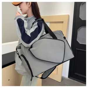 Vue détaillée de sac de sport gris montrant le compartiment à chaussures et la bandoulière.