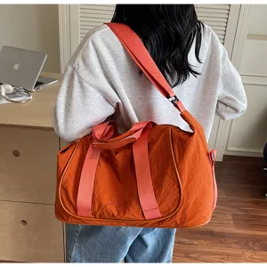 Detail view of orange fitness duffel bag with pink straps, showing sturdy oxford fabric.