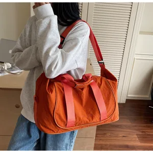 Detail shot of orange yoga duffel bag with red straps, convenient outdoor travel gear.