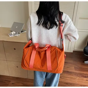 Detail view of the orange oxford cloth travel gym bag showing shoulder strap and fabric texture.