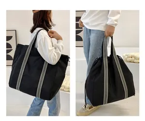 Detail view of large capacity black oxford cloth travel tote bag with striped straps.