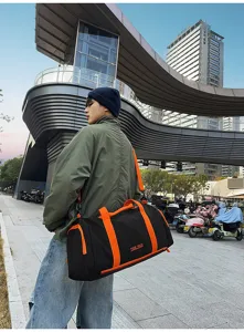 Detailed view of fashionable black and orange colorblock sports duffel bag in modern street scene.