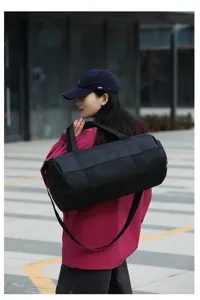 Outdoor detail view of black cylindrical sports duffel bag, large capacity fitness.