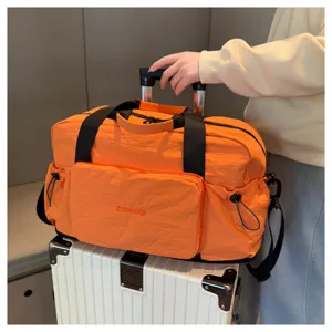 Grand sac de voyage pliable et étanche en orange vif avec séparation humide et poignées solides.