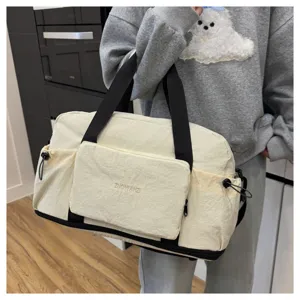 Vue détaillée d'un grand sac de voyage avec des lanières noires et une poche avant pratique.