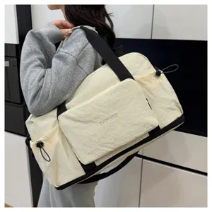 Détail du grand sac de voyage avec tissu blanc cassé, sangles noires et poches fonctionnelles.