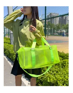Outdoor detail shot of a neon green PVC mesh travel duffel bag, showing large capacity and strap.