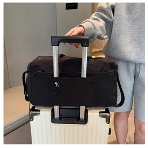 Detail shot of black travel duffel bag showing luggage sleeve feature on suitcase handle.