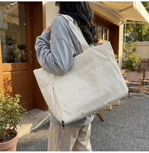 Outdoor lifestyle detail view of a minimalist quilted casual shoulder tote bag in off-white.