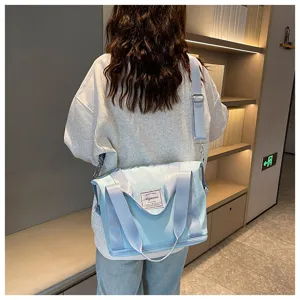 Detail view of light blue travel fitness bag with adjustable strap and stitched woven brand label.