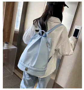 Dettaglio ravvicinato dello zaino casual in tessuto oxford azzurro in una scena interna.