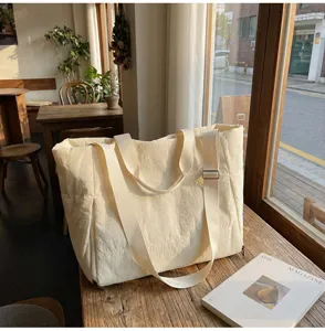 Detailed view of the minimalist beige canvas tote bag with comfortable shoulder straps.