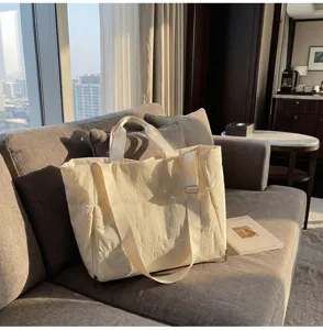 Detailed view of a beige large-capacity tote bag with adjustable strap and side zipper.