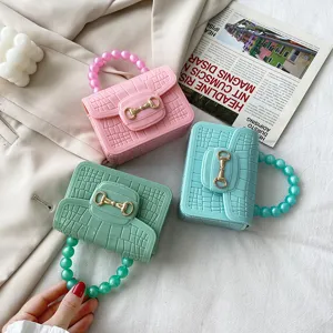 Bonbonfarbene PVC Jelly Handtasche mit Krokodilmuster, Perlenhenkel und Metallverschluss.