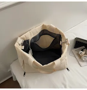 Detailed view of large beige canvas tote bag with multiple compartments and zipper closure.