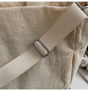Beige nylon tote bag adjustable shoulder strap detail, durable wide fabric strap hardware.