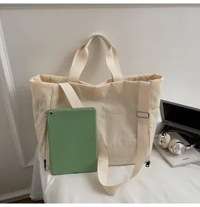 Detail shot of a casual beige padded tote bag with shoulder strap, large capacity and modern design.