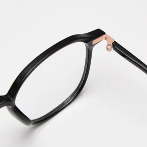 Primer plano de la delicada bisagra de metal en una elegante montura de gafas negra TR90.