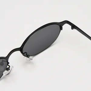 Gros plan sur la monture de lunettes de soleil ovale en métal noir avec plaquettes.