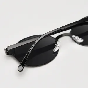 Vue détaillée de lunettes de soleil ovales en métal noir tendance avec verres sombres.