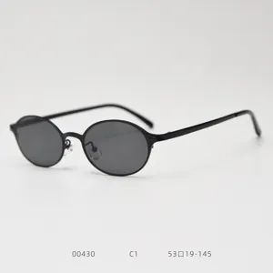 Détail de lunettes de soleil vintage ovales en métal, monture noire, look rétro classique.