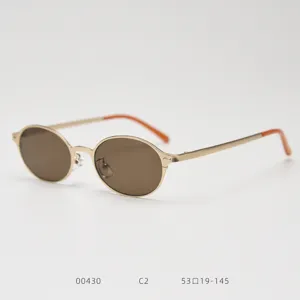 Gros plan de petites lunettes de soleil en metal vintage ovales avec verres marron et embouts.