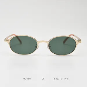 Gros plan de lunettes de soleil rétro à monture ovale en métal doré et verres vert foncé.