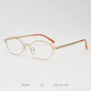 Détails d'une monture de lunettes vintage ovale en métal avec des embouts de branches orange.