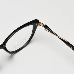 Cat eye eyeglasses frame detail close up, black and gold hinge design, trendy optical eyewear.