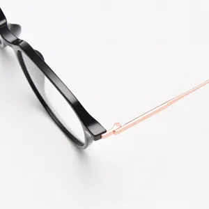 Close-up detail of stylish black frame glasses with rose gold temples, modern minimal design.