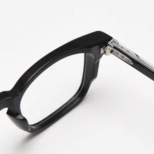 Detailed close-up of black acetate eyeglasses frame showing hinge and rim craftsmanship.