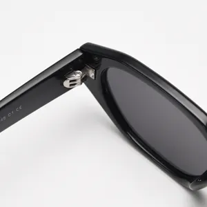 Vue de détail de lunettes de soleil polygonales noires, charnière en métal chic.