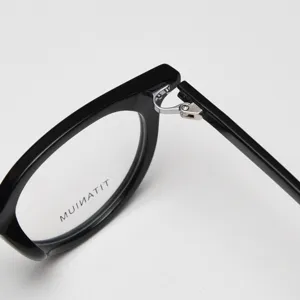 Close-up detail view of black acetate optical glasses frame featuring metallic hinge design.
