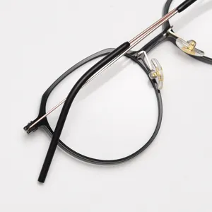 Close-up detail of stylish black round eyeglasses frame with thin metal temples and pads.