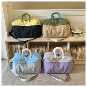 Detalle de bolsa de viaje grande, diseño en bloque de color con asas resistentes y correa ajustable.