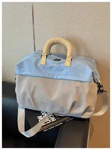 Vista detallada de una gran bolsa de viaje bicolor con comodo mango para uso diario.