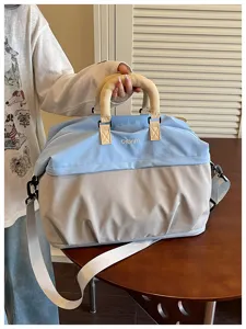 Vista detallada que muestra el asa de la bolsa de viaje bicolor y su correa ajustable.