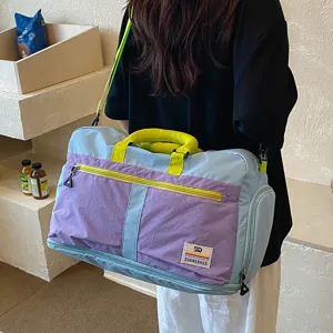 Close-up view of the color-blocked travel duffel bag with reinforced handles and front zip pocket.