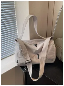 Vue détaillée du sac de voyage gris clair, avec bandoulière large et fermetures à glissière.
