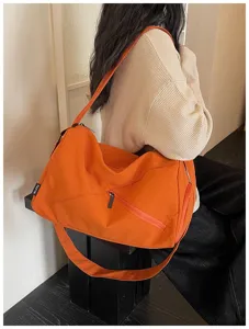 Détail de sac de voyage orange, grand sac bandoulière de sport et fitness pour femmes.