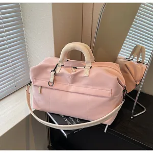 Pink travel duffel bag detail showing front zipper pocket, beige handle and strap for trips.