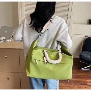 Detailed view of the stylish green travel duffel bag with shoulder strap and dual handles.