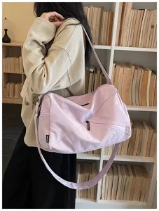 Détail de sac de voyage bandoulière violet clair, poche zippée, idéal pour sport et yoga.