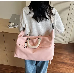 Detail view of a large capacity pink travel duffel bag showing comfortable handle and strap.
