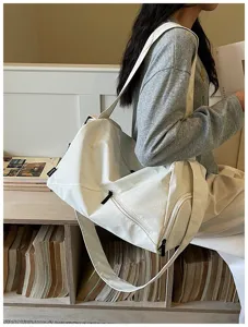Vue détaillée du sac de voyage blanc en toile avec poche latérale zippée et bandoulière.