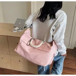 Pink travel duffel bag detail showcasing spacious interior, stylish shoulder strap and handle.