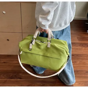 Close-up detail of the stylish green travel duffel bag with white straps and metal hardware.