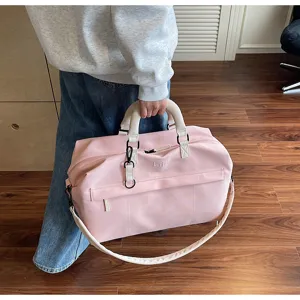 Close-up of a stylish pink travel duffel bag with large capacity, handles and shoulder strap.